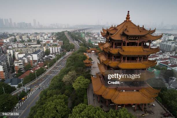 This photo taken on April 15, 2018 shows participants running past the Yellow Crane Tower as they compete in the Wuhan Marathon in Wuhan in China's...