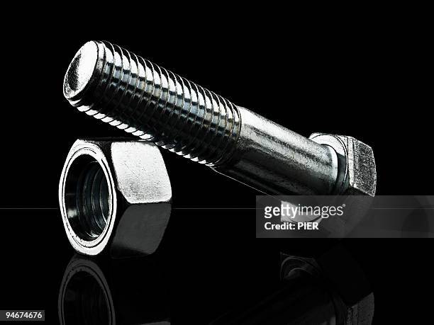 large steel nut and bolt sat on black background - nut fastener stock-fotos und bilder