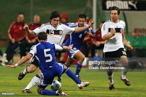 Thomas Stock of Germany advances with the ball between two Israeli players during their Under-18 international friendly match on December 17, 2009 in...