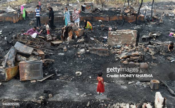 Rohingya refugees look for their belongings in New Delhi on April 16 following a fire that broke out at their camp early April 15 that left around...
