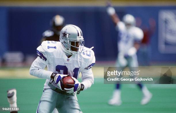 Cornerback Deion Sanders of the Dallas Cowboys runs with the football as he returns a punt 38 yards during a game against the Pittsburgh Steelers at...