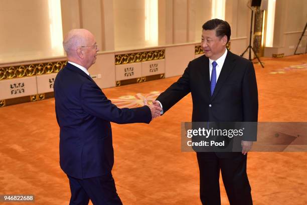 Klaus Schwab, Founder and Executive Chairman of the World Economic Forum, shakes hands with Chinese President Xi Jinping before their meeting at the...