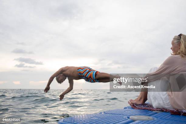 woman watches man dive into sea - shorts down stock pictures, royalty-free photos & images