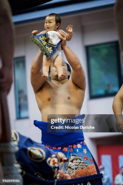 Yokuzuna wrestler hols a baby during 'Honozumo' ceremonial on April 16, 2018 in Tokyo, Japan. This annual offering of a Sumo Tournament to the divine...