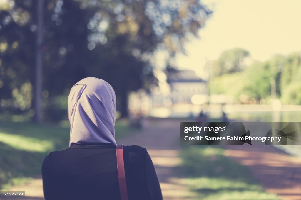 Rear view of a veiled muslim woman walking in forest