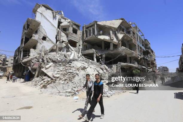 People are seen walking in Douma on the outskirts of Damascus on April 16, 2018 during an organised media tour after the Syrian army has declared...