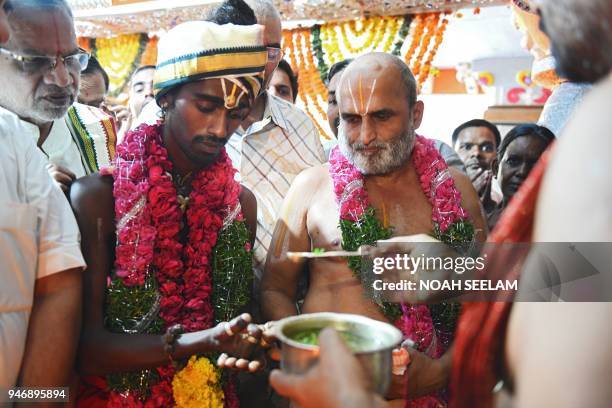 An Indian Hindu priest CS Rangarajan performs rituals along with a Dalit devotee Aditya Parasri after carrying him on his shoulders into the sanctum...