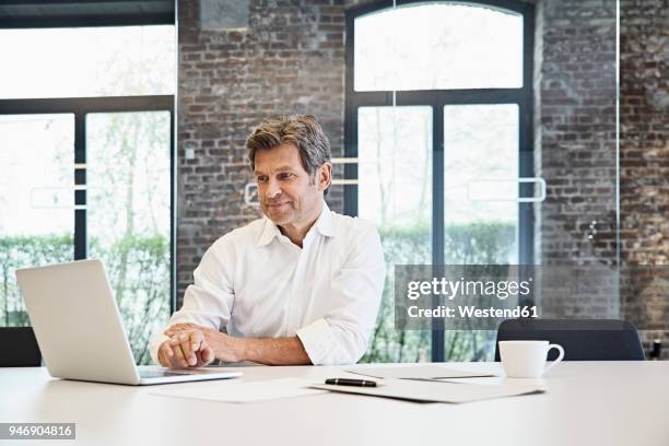 mature businessman using laptop in modern office - camisa branca - fotografias e filmes do acervo
