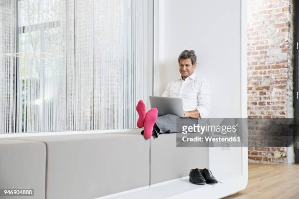 businessman with pink socks using laptop in office - rosa germanica foto e immagini stock