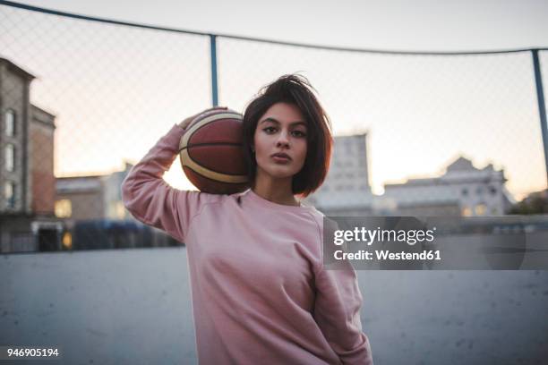 portrait of young woman holding basketball outdoors - sports field fence stock pictures, royalty-free photos & images