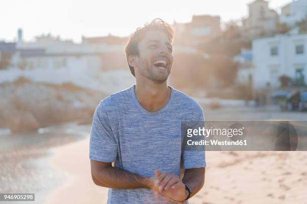 laughing young man on the beach at sunset - barcelona free stockfoto's en -beelden