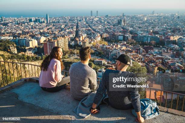 spain, barcelona, three friends sitting on a wall overlooking the city - city wall ストックフォトと画像