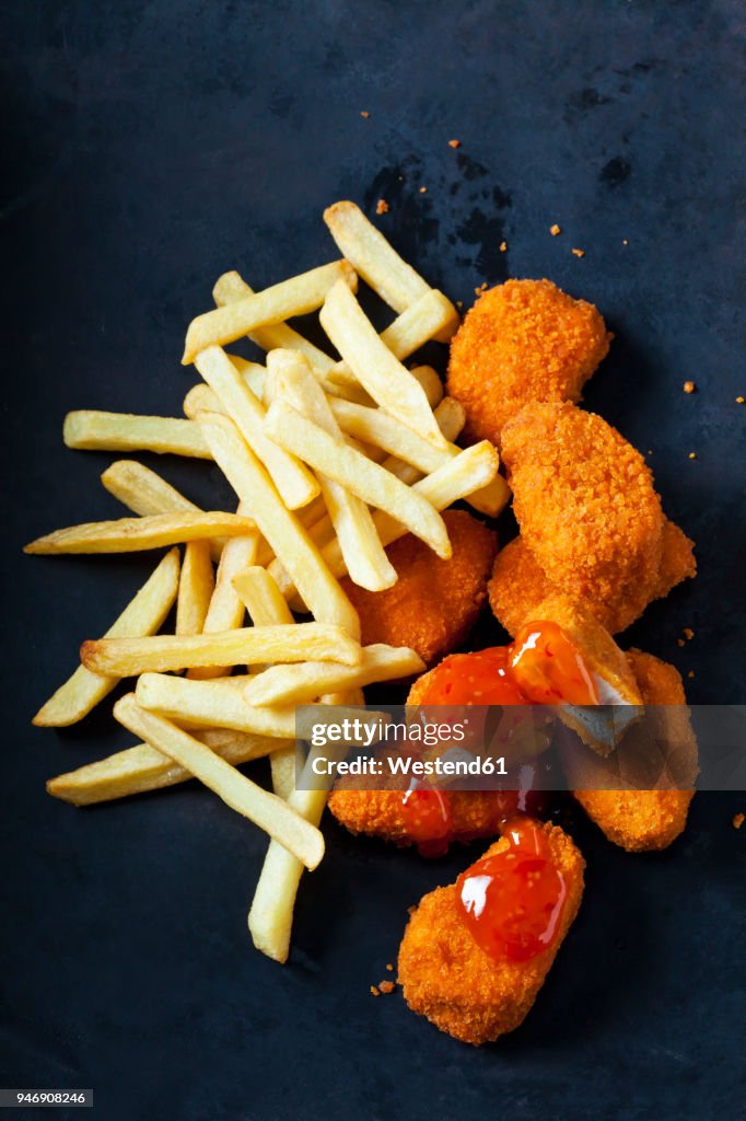 Chicken Nuggets with sweet chili sauce and French Fries on dark ground