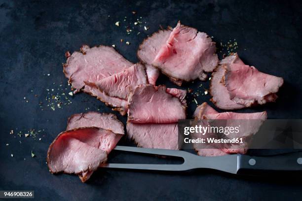six slices of roast beef, herbes and meat fork on dark ground - rosbif photos et images de collection