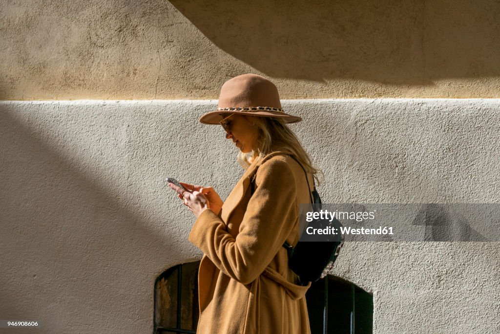 Fashionable young woman at a building using cell phone