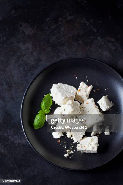 feta, herbes and basil leaves on black plate - feta stock-fotos und bilder