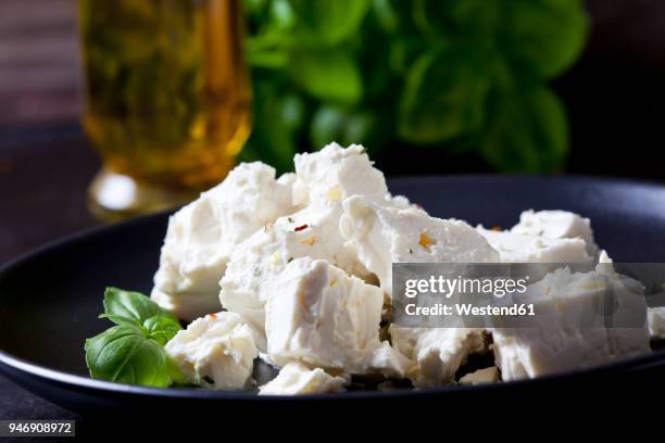 feta, herbes and basil leaves on black plate, close-up - feta stockfoto's en -beelden