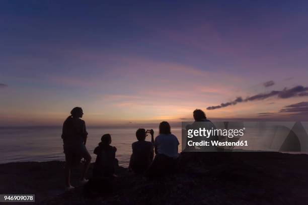 indonesia, bali, lembongan island, friends at ocean coast at dusk - colorful sunset stock-fotos und bilder
