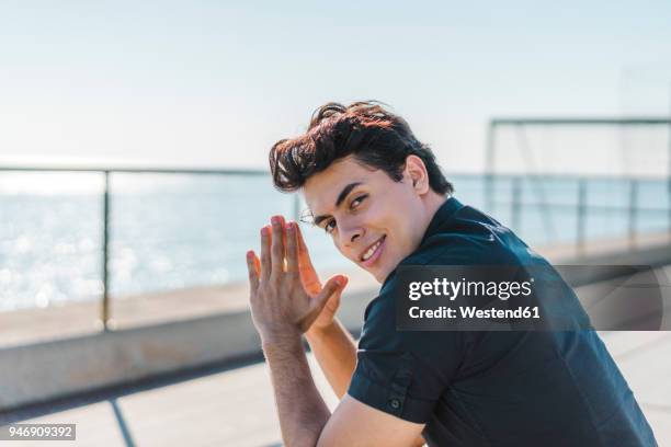 portrait of smiling young man at the coast - arrogant stockfoto's en -beelden