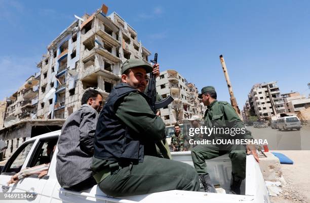 Syrian police sit in the back of a vehicle in Douma on the outskirts of Damascus on April 16, 2018 during an organised media tour after the Syrian...