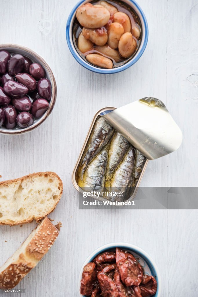 Tin can of sardines in oil, bowls of pickled vegetables and slices of bread