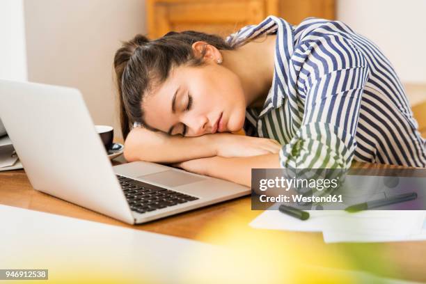 young woman sleeping in front of her laptop at home - woman sleeping table stock pictures, royalty-free photos & images