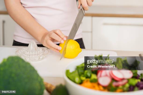young woman cutting a lemon for a fresh salad dressing - dressing room stock-fotos und bilder