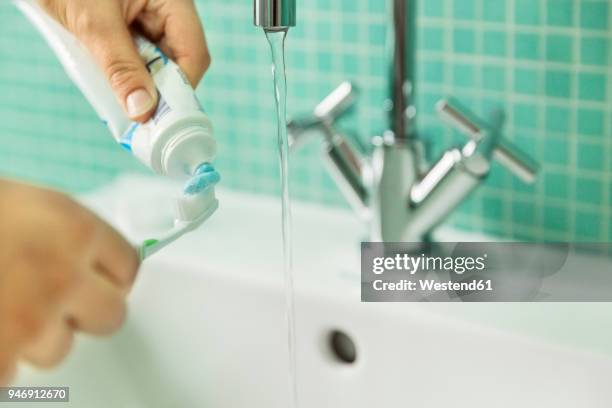 hands putting toothpaste on toothbrush in bathroom - 歯みがき粉 ストックフォトと画像