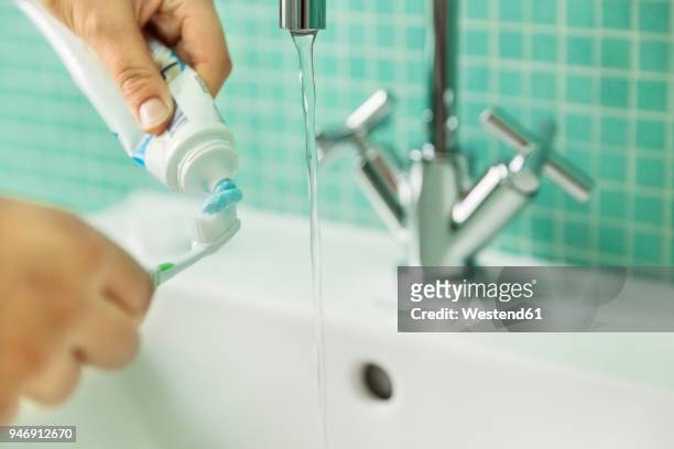 hands putting toothpaste on toothbrush in bathroom - pasta de dentes imagens e fotografias de stock