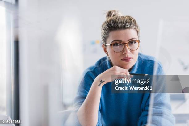 portrait of young woman wearing glasses in office - designer profissional fotografías e imágenes de stock