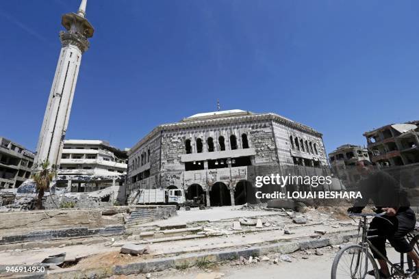 Syrian man cycles past the Grand Mosque in Douma on the outskirts of Damascus on April 16, 2018 during an organised media tour after the Syrian army...