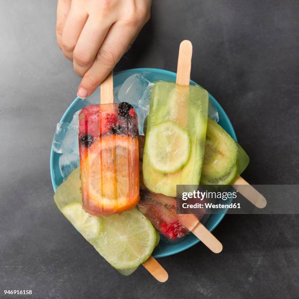woman's hand taking orange berry popsicle - colorful vegetables summer stock-fotos und bilder