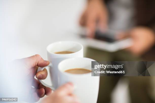 close-up of woman holding coffee cups while man using tablet in office - kafferast bildbanksfoton och bilder