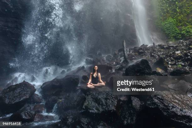 indonesia, bali, young woman practicing yoga at sekumpul waterfall - bali waterfall stock pictures, royalty-free photos & images