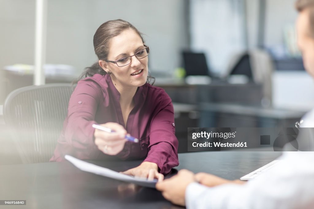 Woman showing contract to client at desk
