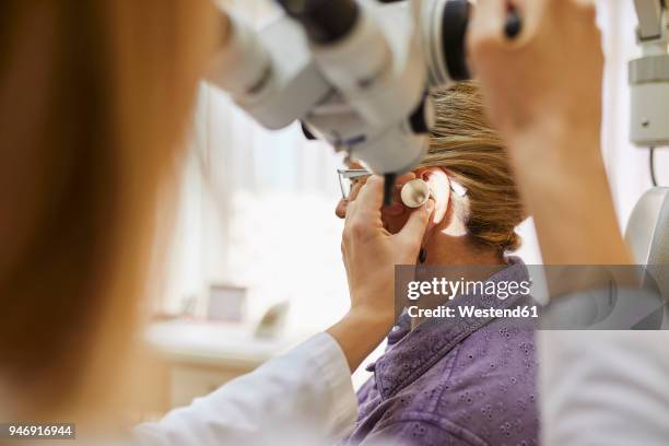 ent physician examining ear of a senior woman - doctor listener imagens e fotografias de stock