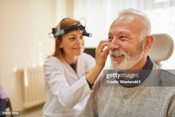 ent physician examining ear of a senior man - doctor listener imagens e fotografias de stock