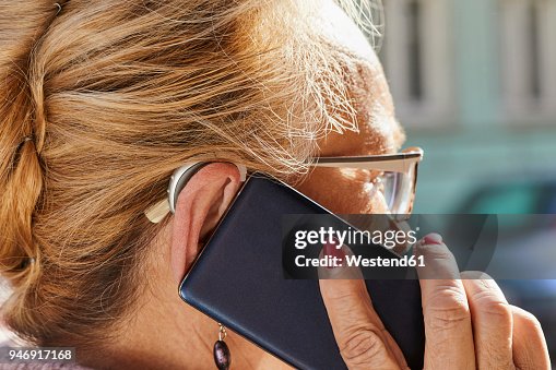 Close-up of senior woman with hearing aid using smartphone Close-up of senior woman with hearing aid using smartphone