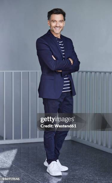 portrait of smiling businessman with stubble wearing blue suit - grauer anzug stock-fotos und bilder