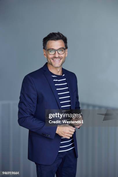 portrait of smiling businessman with stubble wearing blue suit and glasses - giacca foto e immagini stock