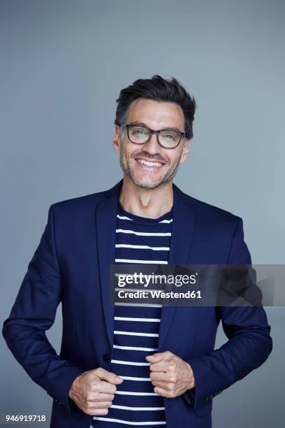 portrait of laughing businessman with stubble wearing blue suit coat and glasses - grey suit foto e immagini stock