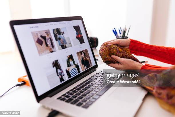 close-up of fashion designer in studio with laptop examining fabric - blogger with laptop foto e immagini stock