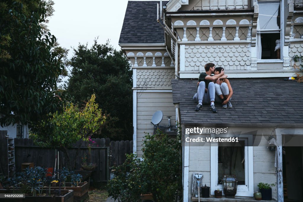 Couple sitting on roof kissing