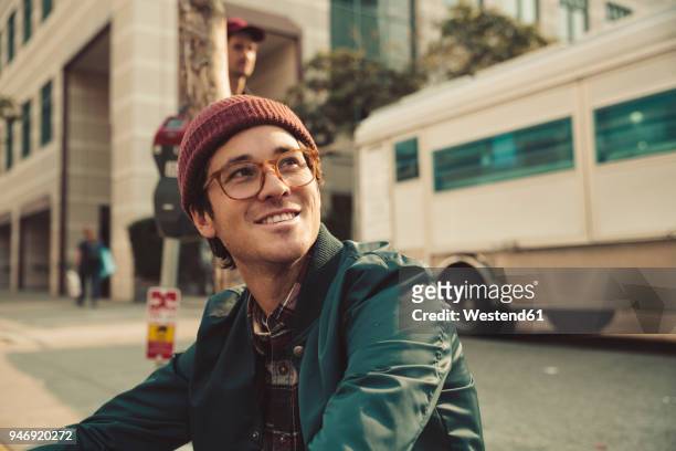 portrait of stylish young man sitting on sidewalk - jeunes hommes photos et images de collection