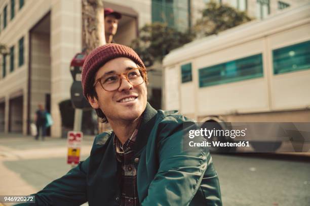 portrait of stylish young man sitting on sidewalk - 2018 glasses ストックフォトと画像