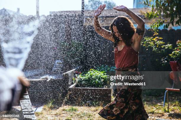 water splashing on young woman in backyard - refreshing stock pictures, royalty-free photos & images