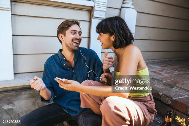 happy young man and woman with smartphone and earphones - sharing headphones stock pictures, royalty-free photos & images