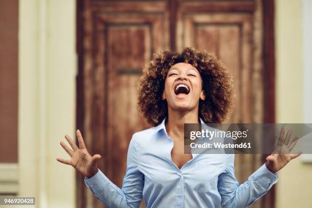 portrait of woman with afro hairstyle screaming outdoors - beugen oder biegen stock-fotos und bilder