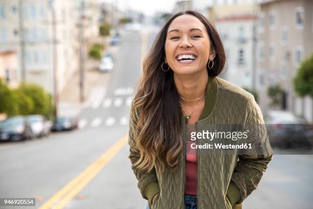 portrait of laughing young woman on the street - solo una donna giovane foto e immagini stock