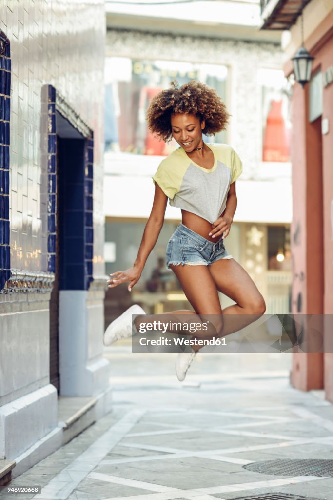 Happy woman with afro hairstyle jumping in a lane